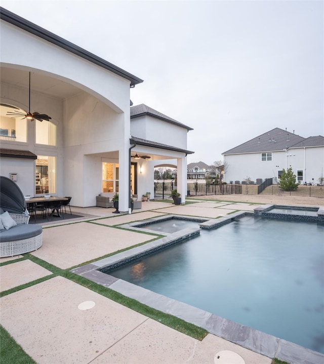 view of pool with fence, outdoor dining area, a pool with connected hot tub, ceiling fan, and a patio area