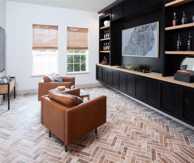 living room with baseboards, brick floor, and a bar