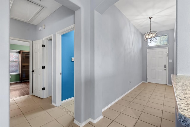 entryway featuring light tile patterned floors, an inviting chandelier, arched walkways, and baseboards