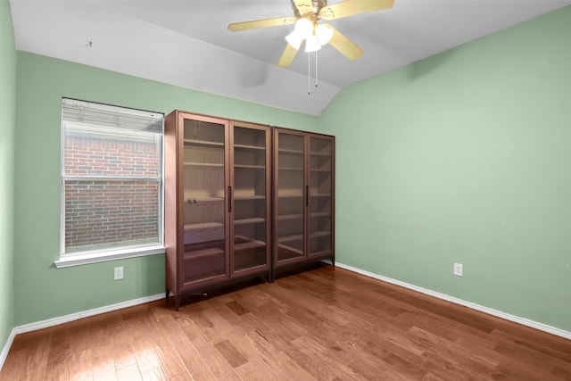 unfurnished bedroom featuring lofted ceiling, ceiling fan, baseboards, and wood finished floors