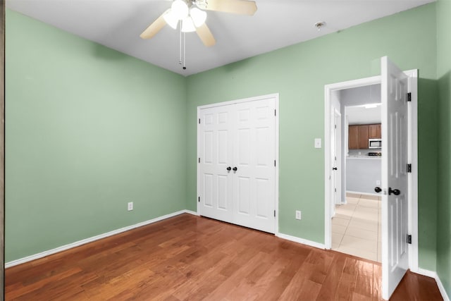 unfurnished bedroom with a ceiling fan, a closet, baseboards, and wood finished floors