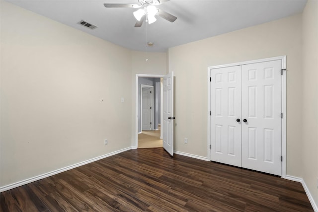 unfurnished bedroom featuring dark wood finished floors, a closet, visible vents, ceiling fan, and baseboards