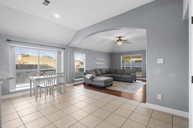 living area with visible vents, arched walkways, baseboards, vaulted ceiling, and light tile patterned flooring