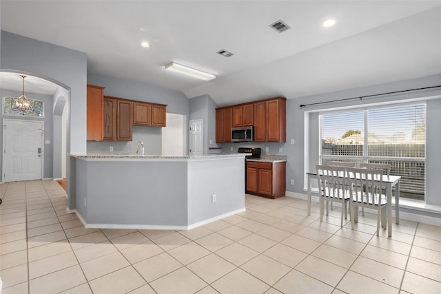 kitchen with arched walkways, stainless steel microwave, visible vents, and brown cabinets