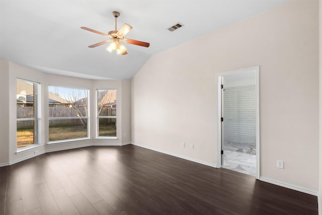 spare room with ceiling fan, visible vents, vaulted ceiling, and dark wood-type flooring