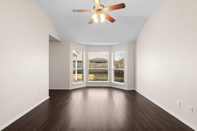 empty room with a ceiling fan, dark wood-style flooring, vaulted ceiling, and baseboards