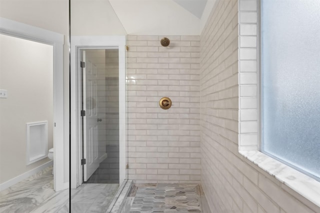 bathroom with marble finish floor, lofted ceiling, toilet, tiled shower, and baseboards