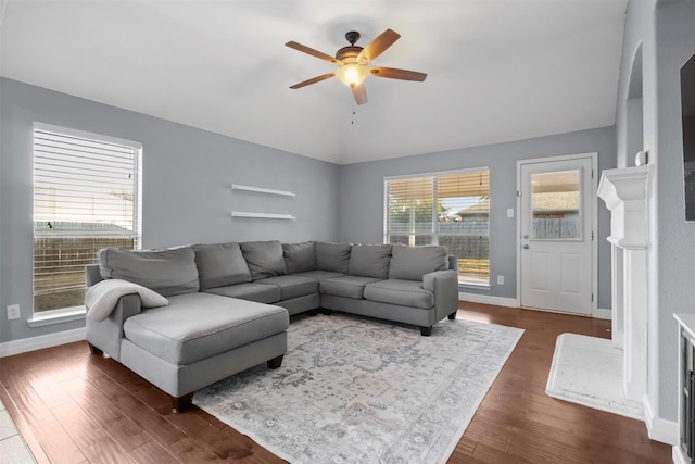 living area featuring dark wood-style floors, lofted ceiling, baseboards, and a ceiling fan