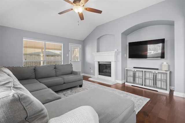 living room with lofted ceiling, baseboards, dark wood-style flooring, and a glass covered fireplace