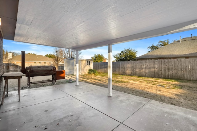 view of patio / terrace featuring a fenced backyard, a storage unit, and an outbuilding