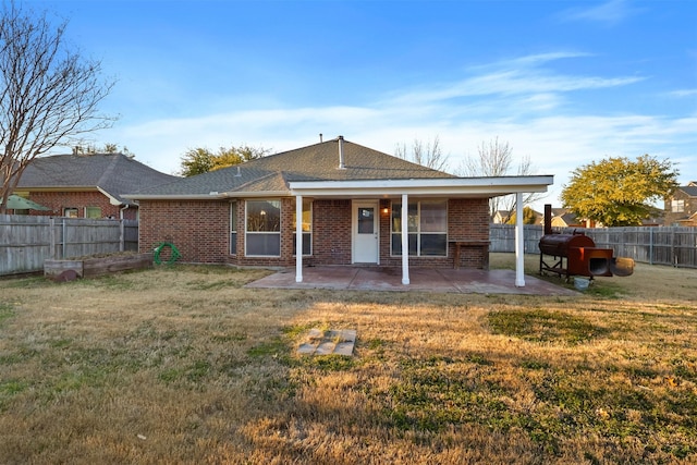 rear view of house featuring brick siding, a lawn, a patio area, and a fenced backyard