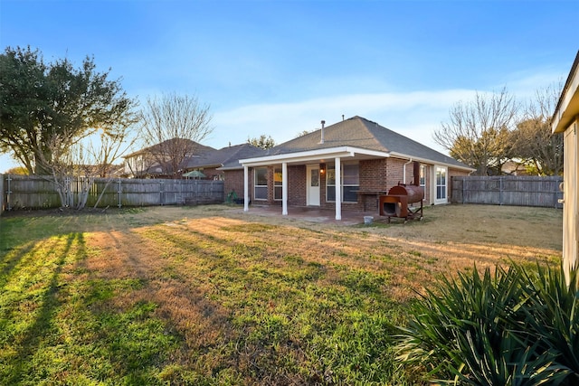 rear view of property with a patio area, a fenced backyard, a lawn, and brick siding