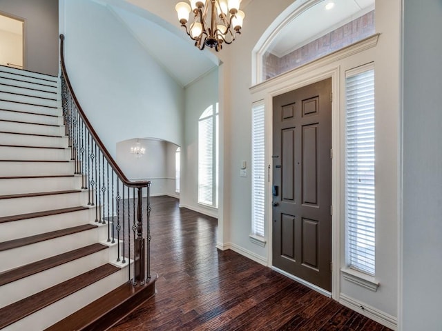 entryway with dark wood-style floors, arched walkways, stairway, a chandelier, and plenty of natural light