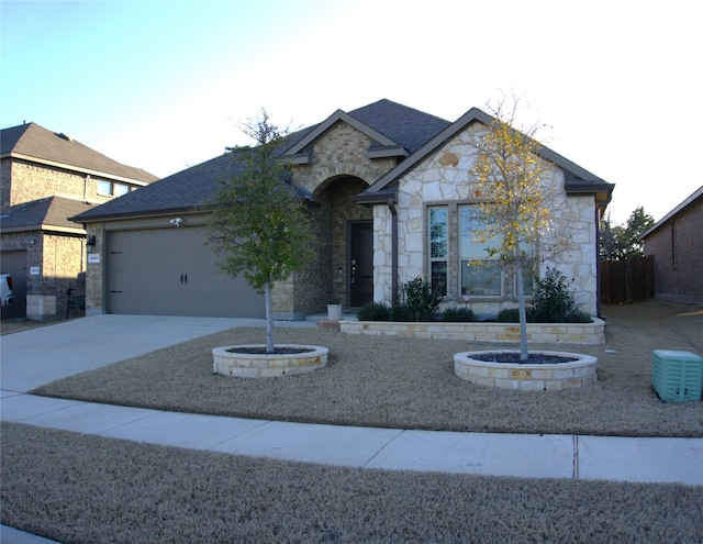 view of front of house featuring a garage, stone siding, a shingled roof, and concrete driveway