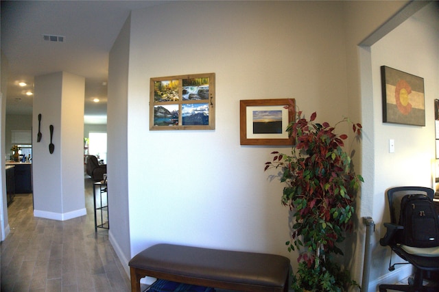 hall with wood finished floors, visible vents, and baseboards