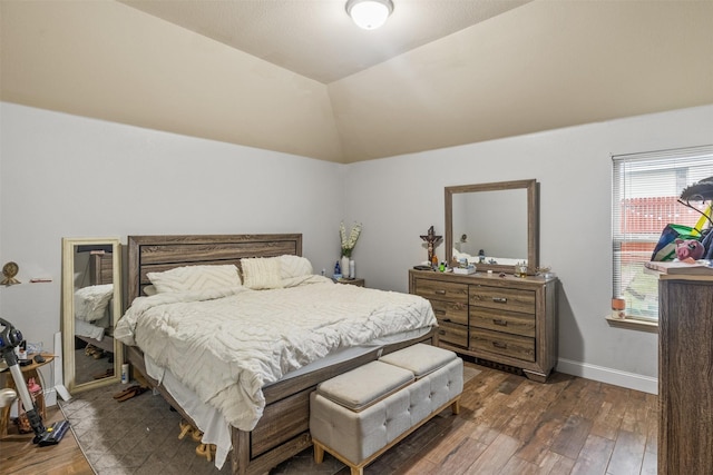 bedroom with lofted ceiling, dark wood finished floors, and baseboards