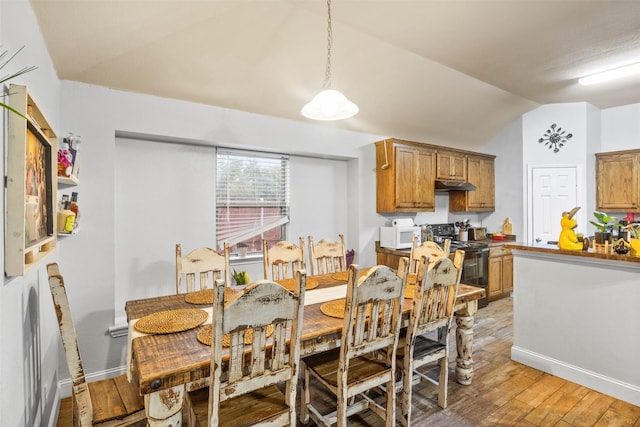 dining area with lofted ceiling, baseboards, and wood finished floors