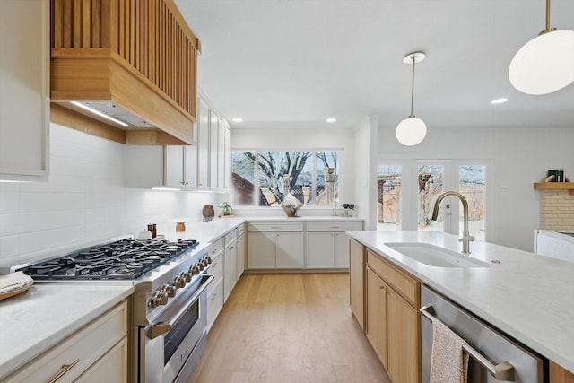 kitchen with stainless steel appliances, light countertops, a sink, and hanging light fixtures