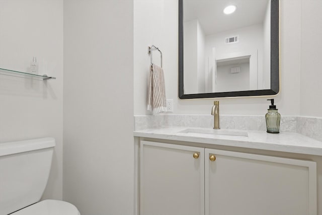 half bathroom with toilet, recessed lighting, visible vents, and vanity