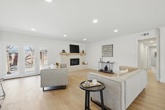 living area with recessed lighting, visible vents, a fireplace, and light wood finished floors