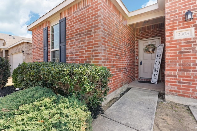 entrance to property with brick siding and an attached garage