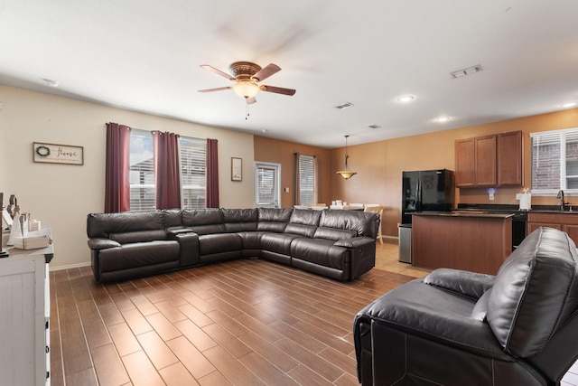 living room with a ceiling fan, visible vents, and wood finished floors