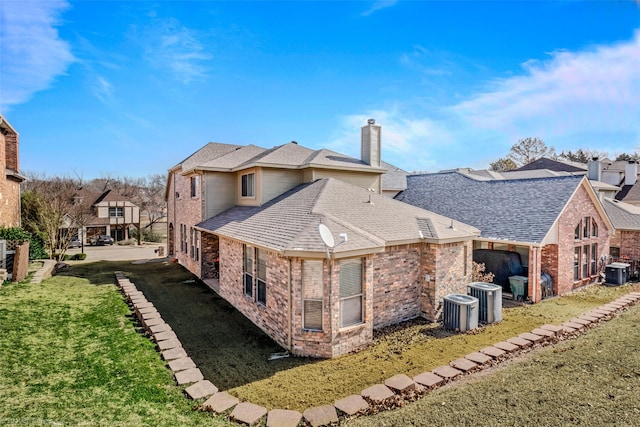 rear view of house featuring a chimney, a shingled roof, a lawn, central AC unit, and a residential view