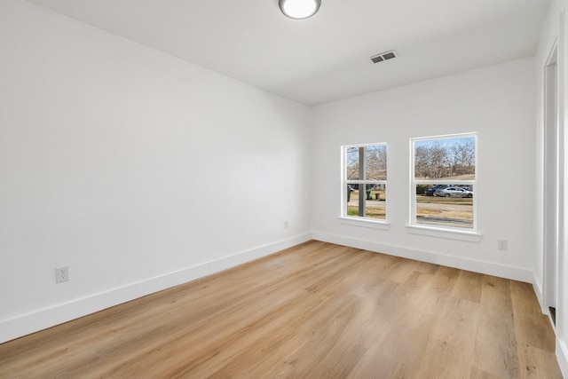 unfurnished room with light wood finished floors, baseboards, and visible vents