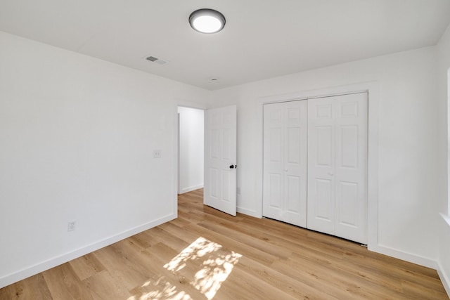 unfurnished bedroom featuring light wood-style flooring, a closet, visible vents, and baseboards