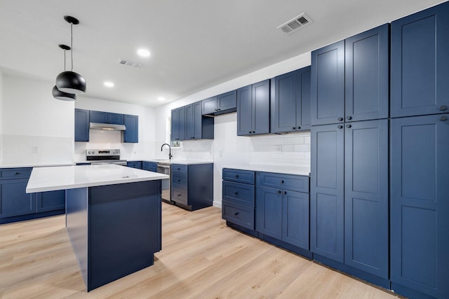 kitchen featuring a center island, decorative light fixtures, stainless steel appliances, light countertops, and a sink