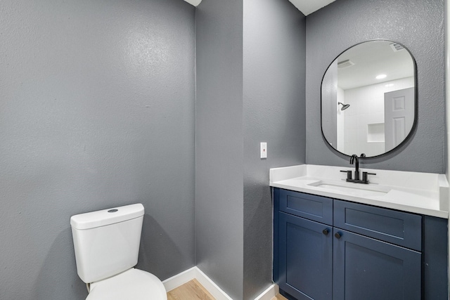 bathroom with baseboards, a textured wall, toilet, wood finished floors, and vanity