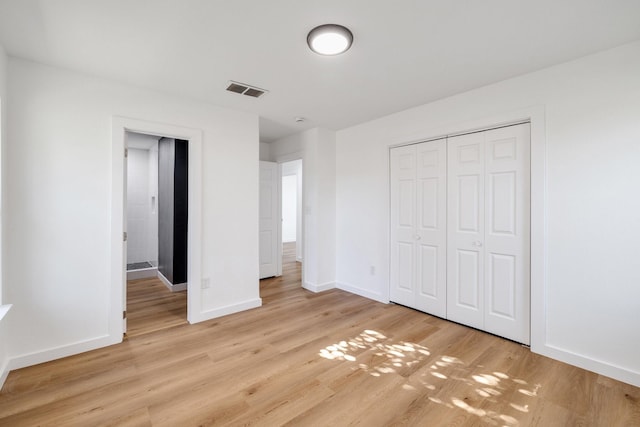 unfurnished bedroom featuring light wood finished floors, visible vents, baseboards, and a closet