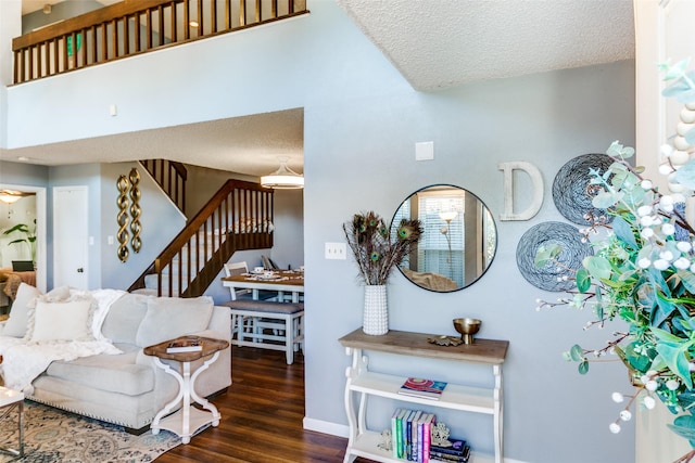 living room featuring stairway, wood finished floors, baseboards, and a textured ceiling