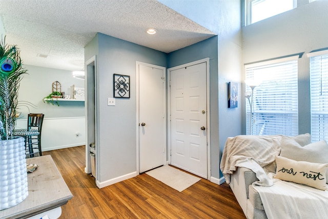 foyer entrance featuring dark wood-style flooring, a textured ceiling, and baseboards