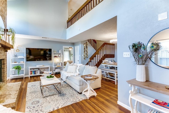 living room with a healthy amount of sunlight, a fireplace, stairway, and wood finished floors