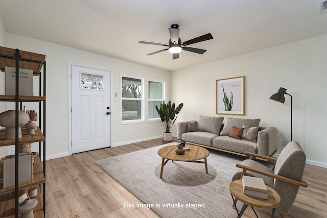 living area featuring baseboards, visible vents, ceiling fan, and wood finished floors