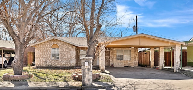 single story home with concrete driveway, brick siding, fence, and an attached carport