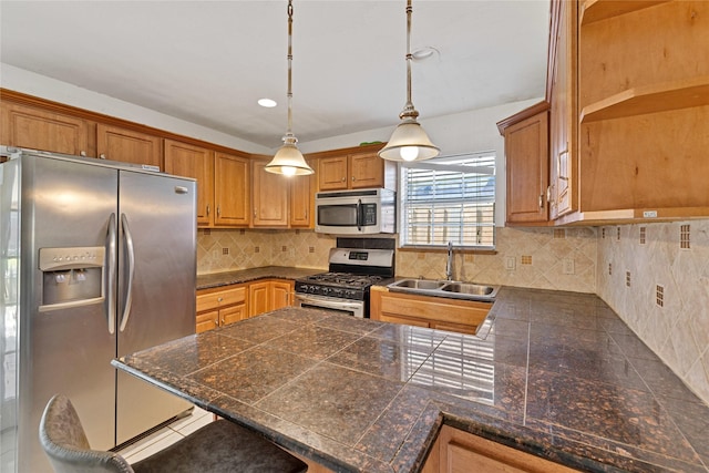 kitchen featuring brown cabinetry, appliances with stainless steel finishes, hanging light fixtures, a peninsula, and a sink