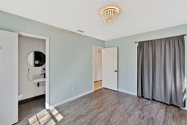 unfurnished bedroom featuring dark wood-type flooring, visible vents, and baseboards