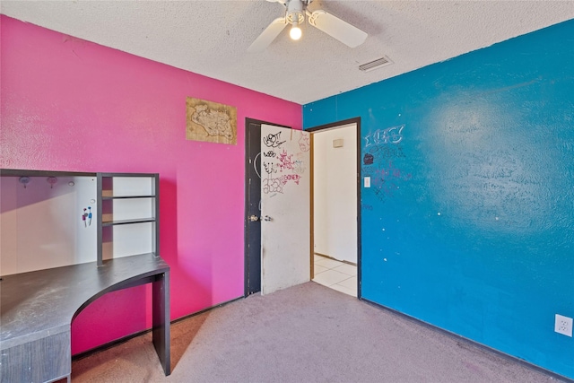 unfurnished bedroom with a textured ceiling, ceiling fan, a textured wall, light colored carpet, and visible vents