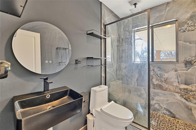 bathroom featuring a marble finish shower, a sink, and toilet