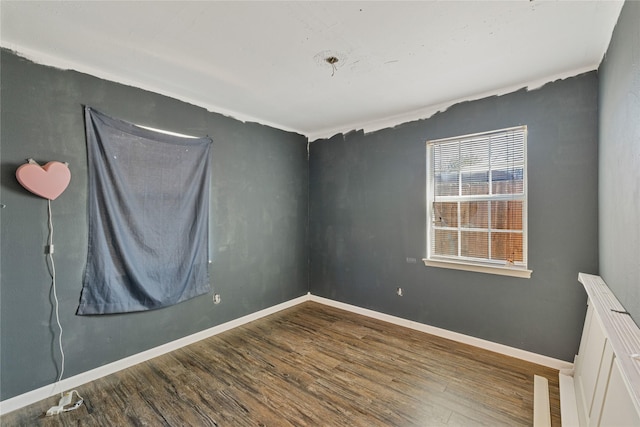 spare room with baseboards and wood finished floors