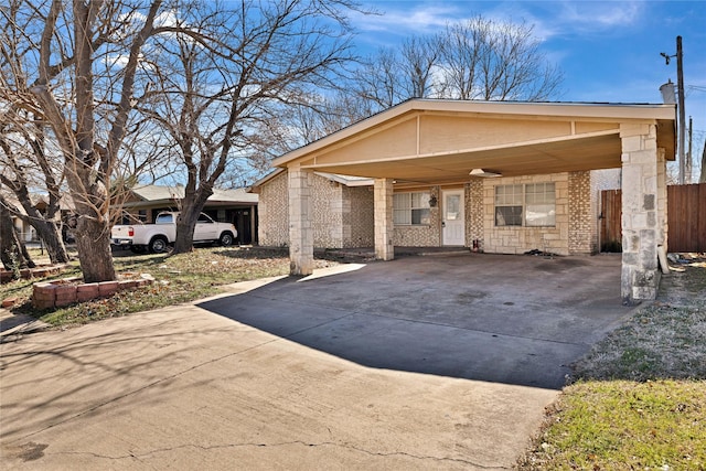 view of front of house featuring driveway, fence, a carport, and brick siding