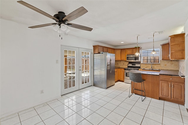 kitchen with a peninsula, hanging light fixtures, french doors, appliances with stainless steel finishes, and brown cabinets