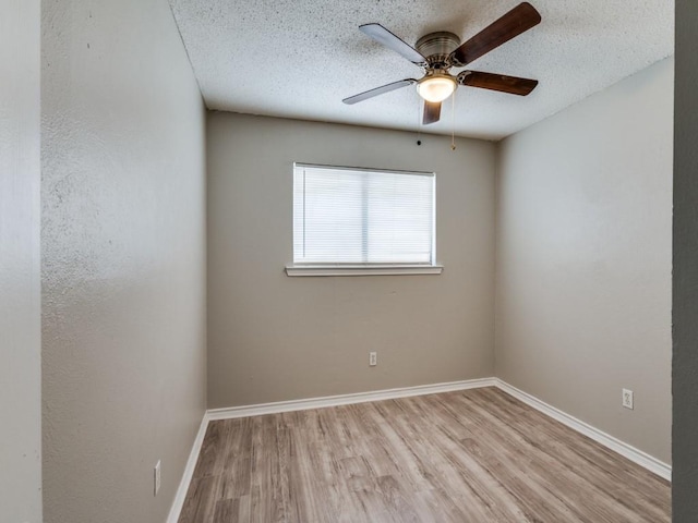 empty room featuring a ceiling fan, light wood-style flooring, baseboards, and a textured ceiling