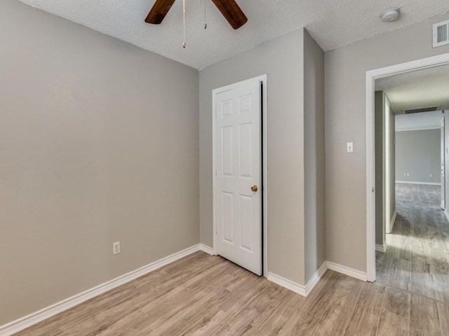 unfurnished bedroom featuring a textured ceiling, light wood-type flooring, visible vents, and baseboards