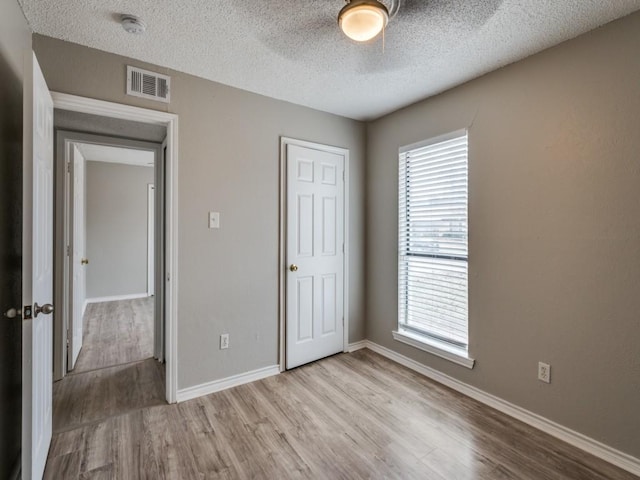 unfurnished bedroom featuring light wood-type flooring, visible vents, and multiple windows