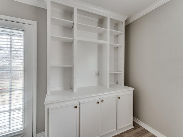 interior space featuring crown molding, baseboards, and wood finished floors