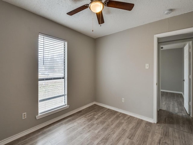 empty room with light wood-style floors, ceiling fan, a textured ceiling, and baseboards