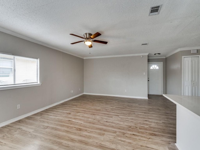 empty room with a ceiling fan, baseboards, visible vents, light wood-type flooring, and crown molding